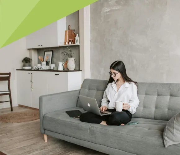Frau auf Sofa mit Kaffee und Laptop